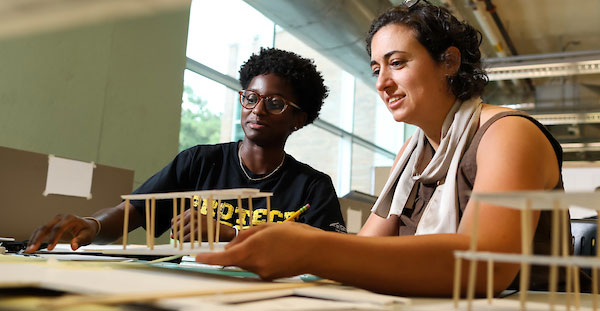 Two architecture students work together on a detailed building model in the College of Architecture and Construction Management