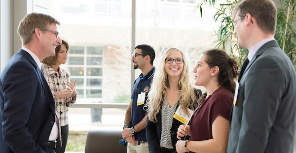 A diverse group of individuals engaged in conversation outside Coles College of Business, fostering collaboration and networking.