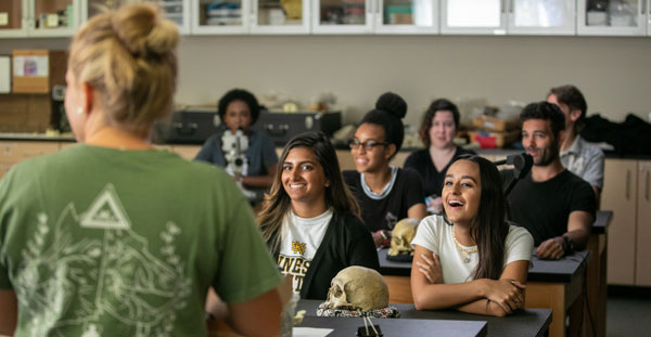 Students actively participating in a classroom discussion with their professor at Kennesaw State College of Humanities and Social Sciences.