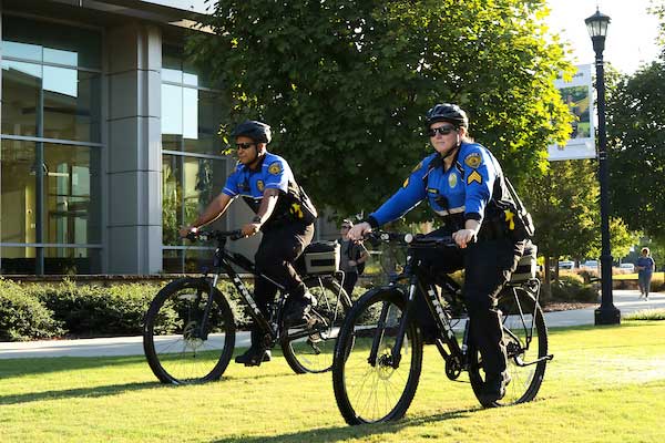two ksu officers on bicycles riding on grass