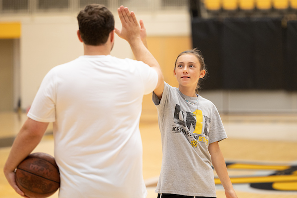 a pair of students in the gym giving a high-five
