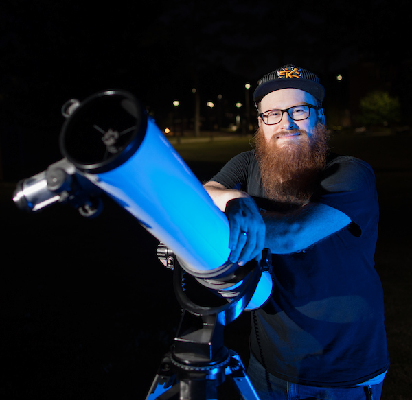 a man with a telescope looking at the night sky