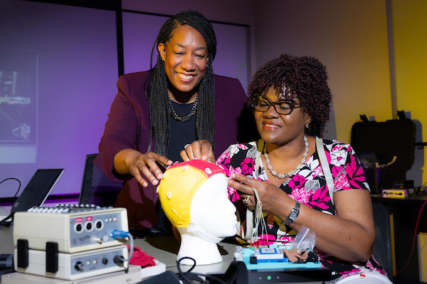 student and professor placing sensors on model of human head