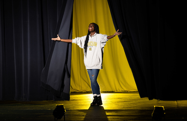 a theatre student on stage with a yellow back-light