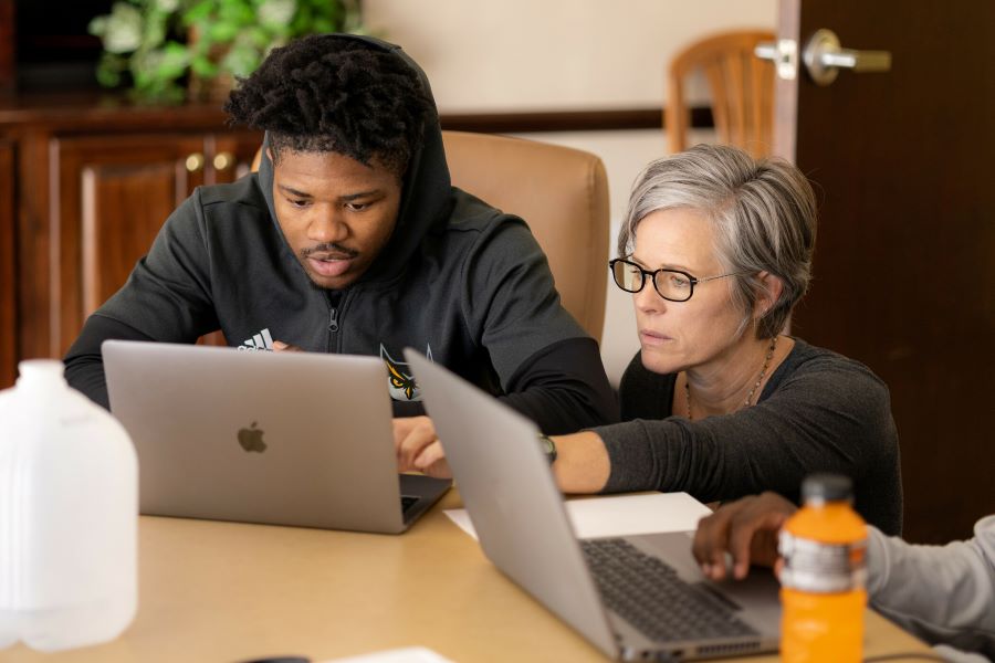 Student and advisor working together on a laptop in a focused session.