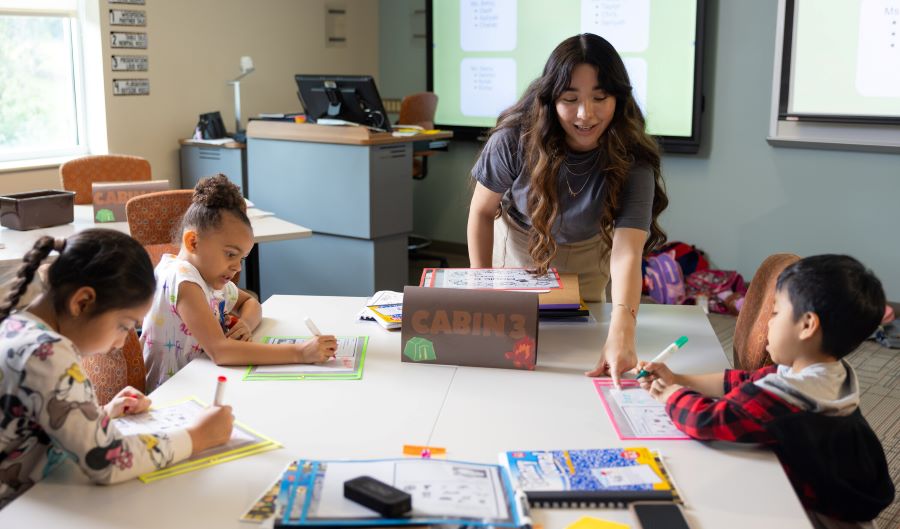 Teacher assisting young students with classroom activities.
