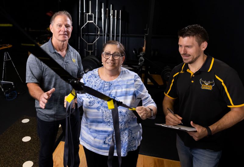 two coaches with student on exercise machine