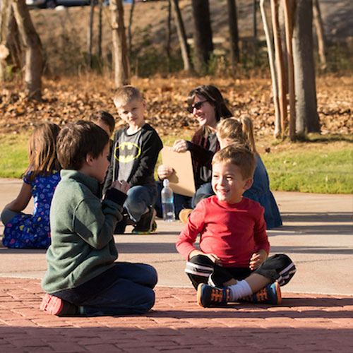 A diverse group of children seated on the ground, engaged in collaborative learning activities in an elementary education setting