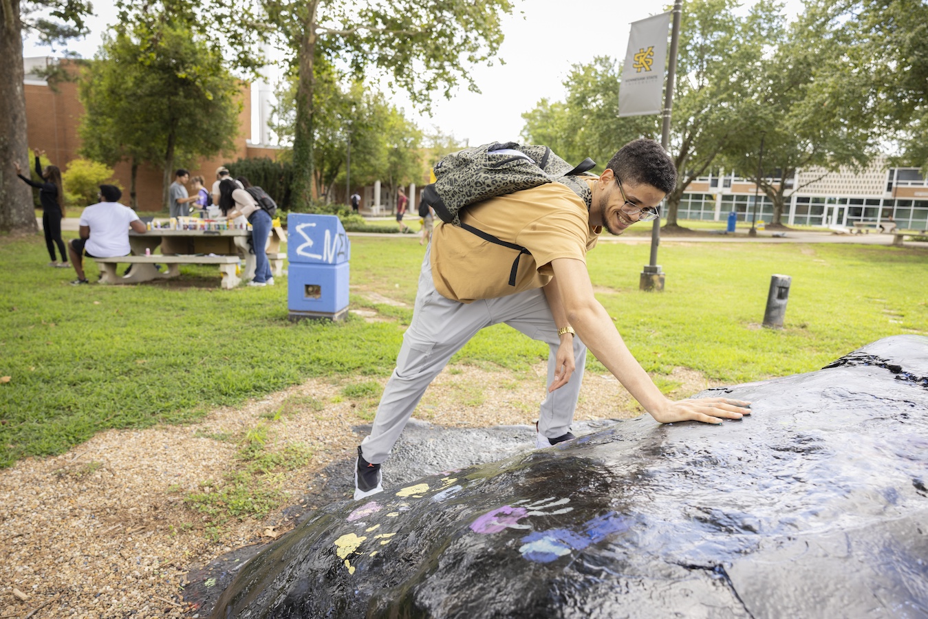 Student placing their hand on the campus rock.