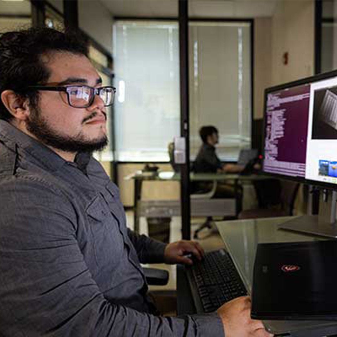 male student looking at computer screen in lab