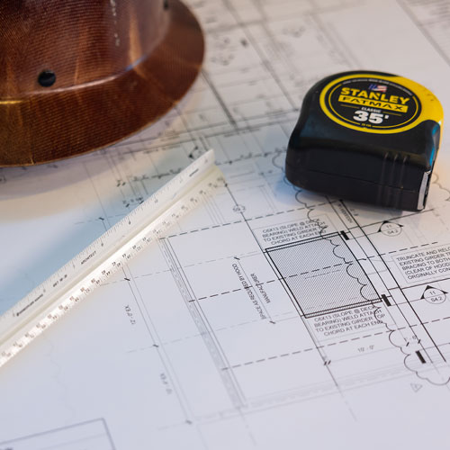 Construction drawing featuring a tape measure and hard hat, symbolizing planning and safety in building projects.