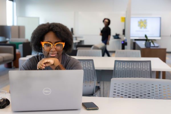 A person using a Dell laptop at a desk with a Kennesaw State University logo on a screen in the background