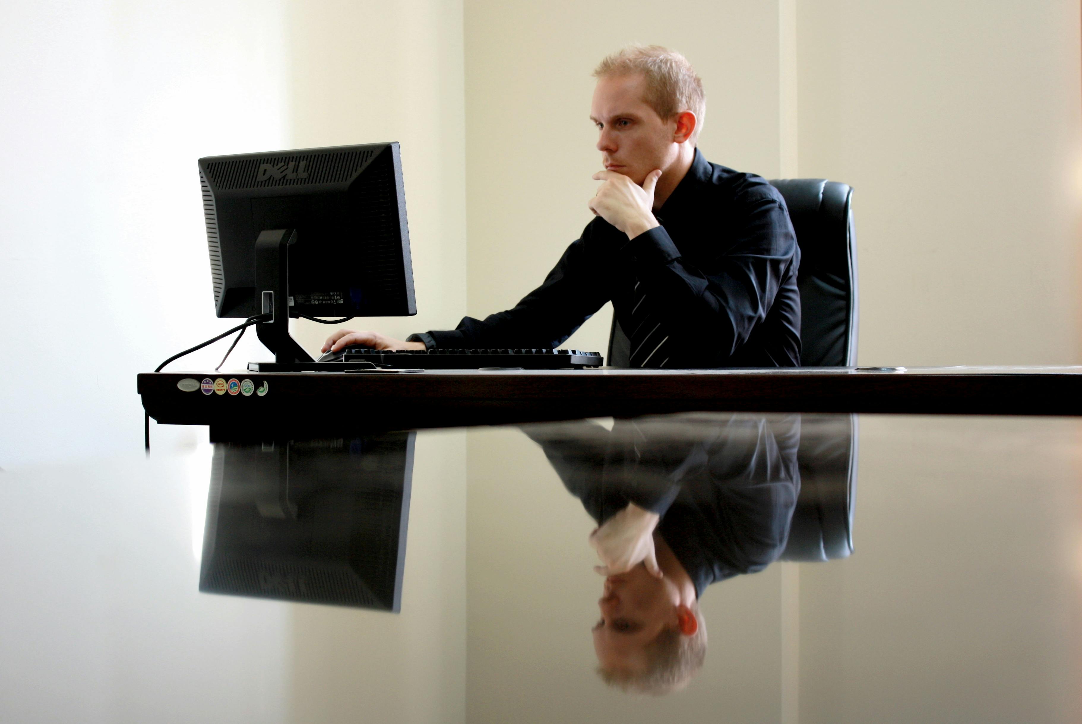 male with hand on face as he look at his black computer