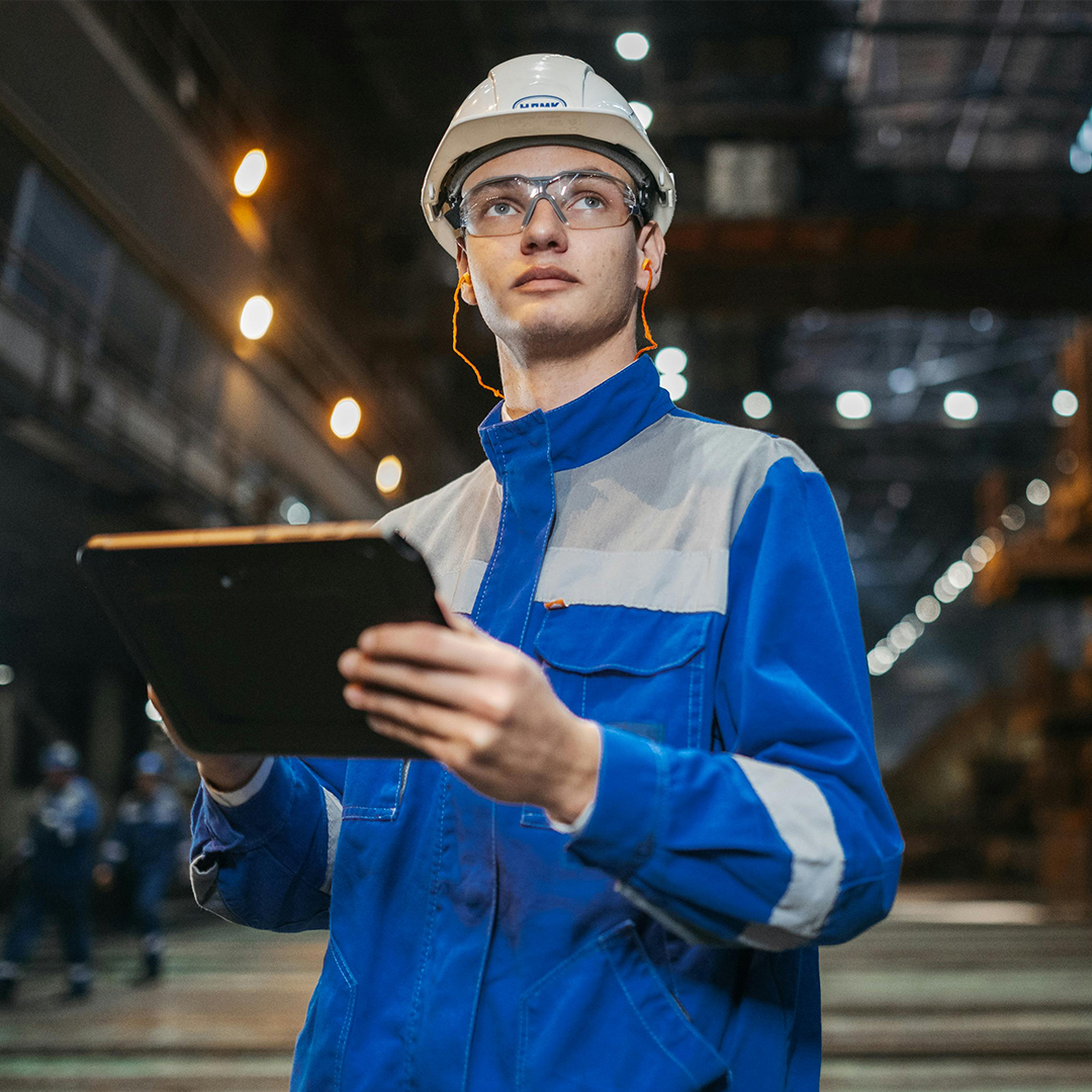 engineer in blue jacket holding paperwork as he assess his factory