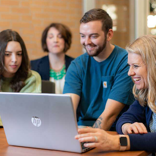 group of students smiling around computer