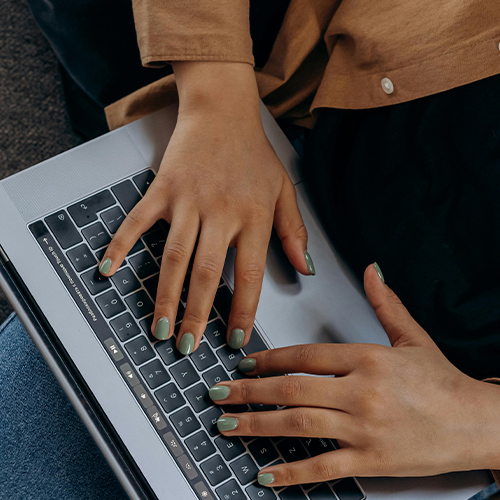 close up of females hands as she works on laptop