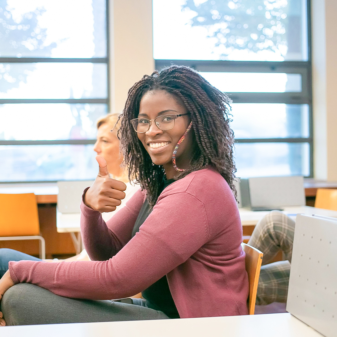 female student with glasses smiling at desk