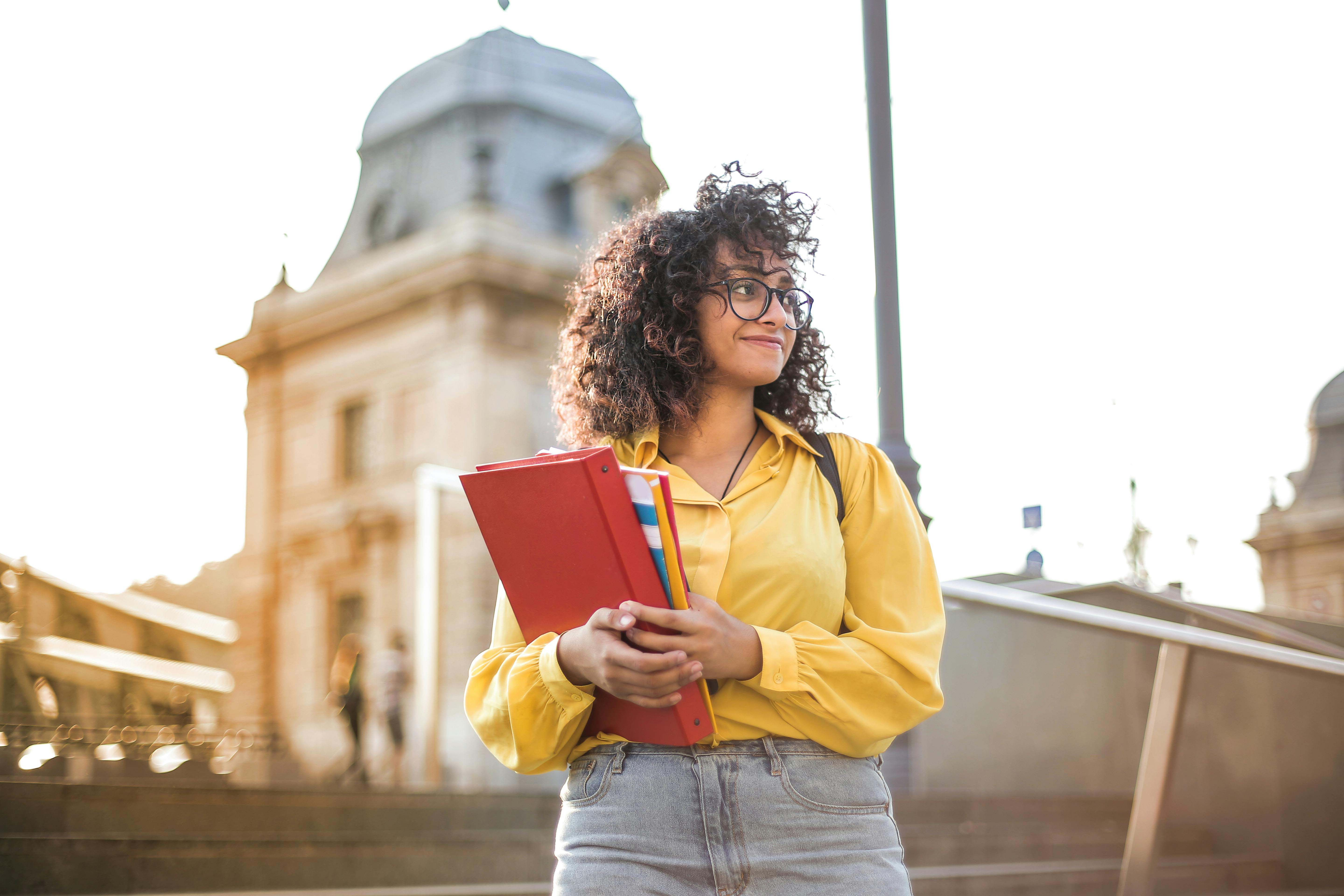 female international student holding books and smiling