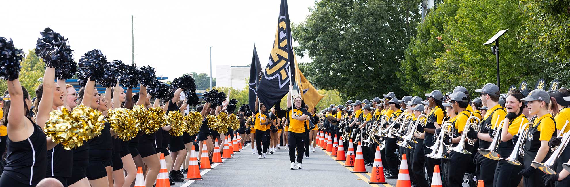 KSU Marching Band and cheer leaders marching with ksu flags