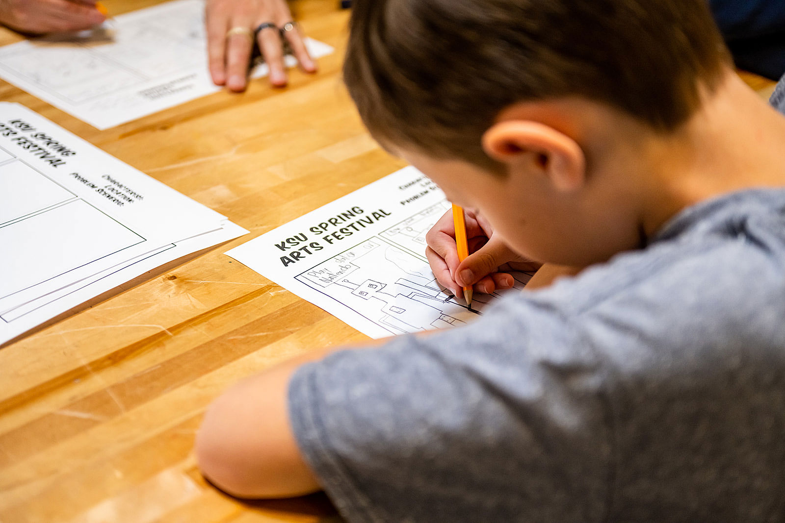 young boy draws a picture at the KSU Spring Arts Festival