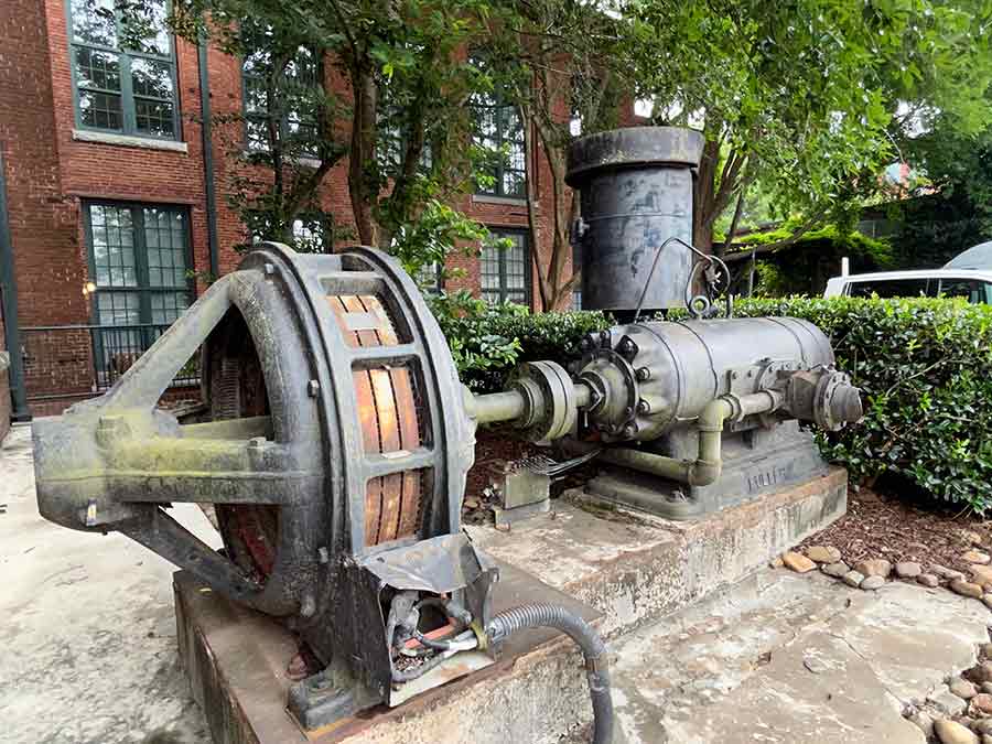 Exterior H Bldg. Condominium NW Entrance, Mill Machinery. 6/29/2022 / Exterior H Bldg. Condominium NW Entrance, Mill Machinery. 6/29/2022. Photograph by Nina Elsas. Courtesy of The Patch Works Art & History Center.