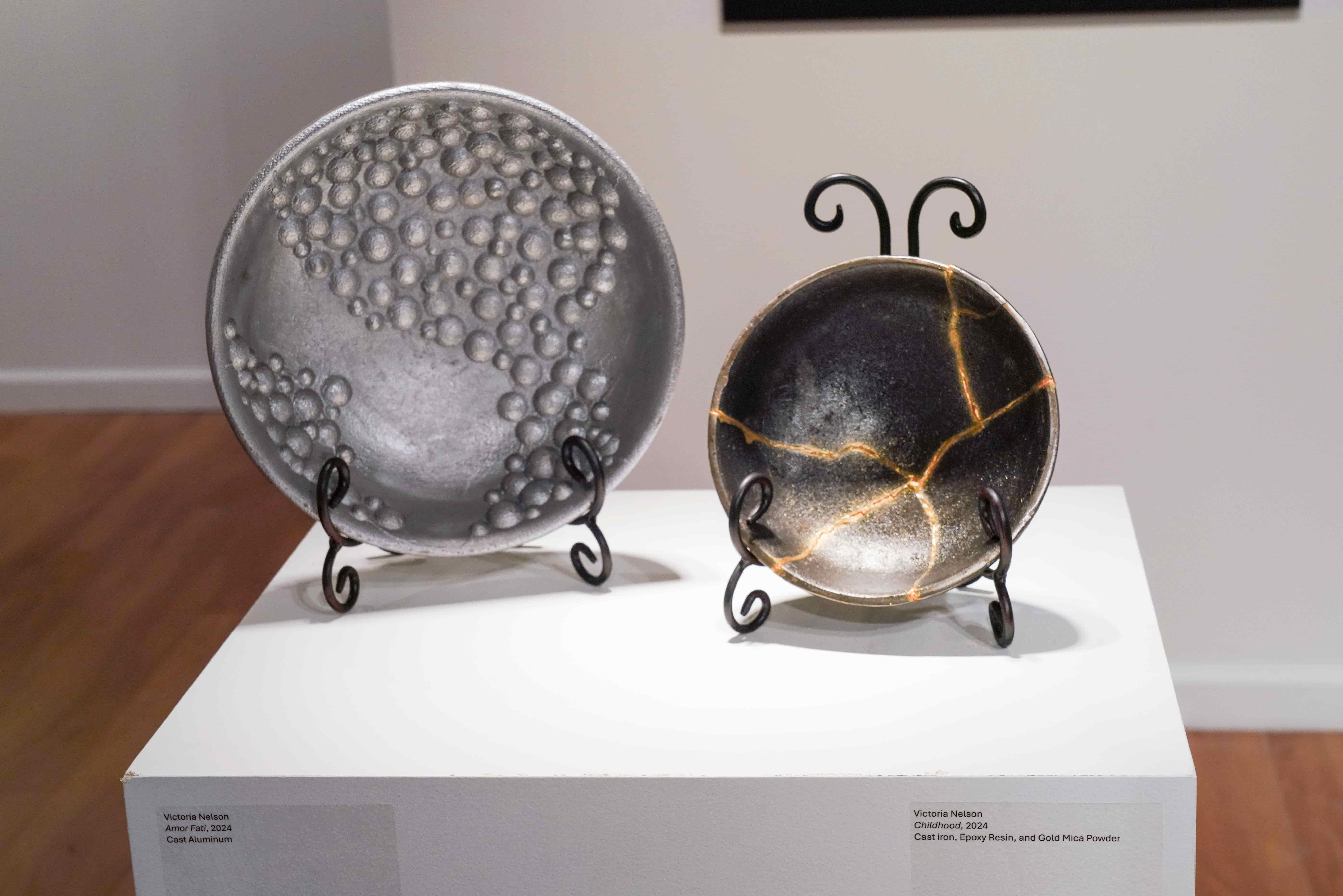 Victoria Nelson, "Amor Fati", 2024. Cast Aluminum. Victoria Nelson, "Childhood", 2024. Cast Iron, Epoxy Resin and Gold Mica Powder. / Victoria Nelson, "Amor Fati", 2024. Cast Aluminum. Victoria Nelson, "Childhood", 2024. Cast Iron, Epoxy Resin and Gold Mica Powder.