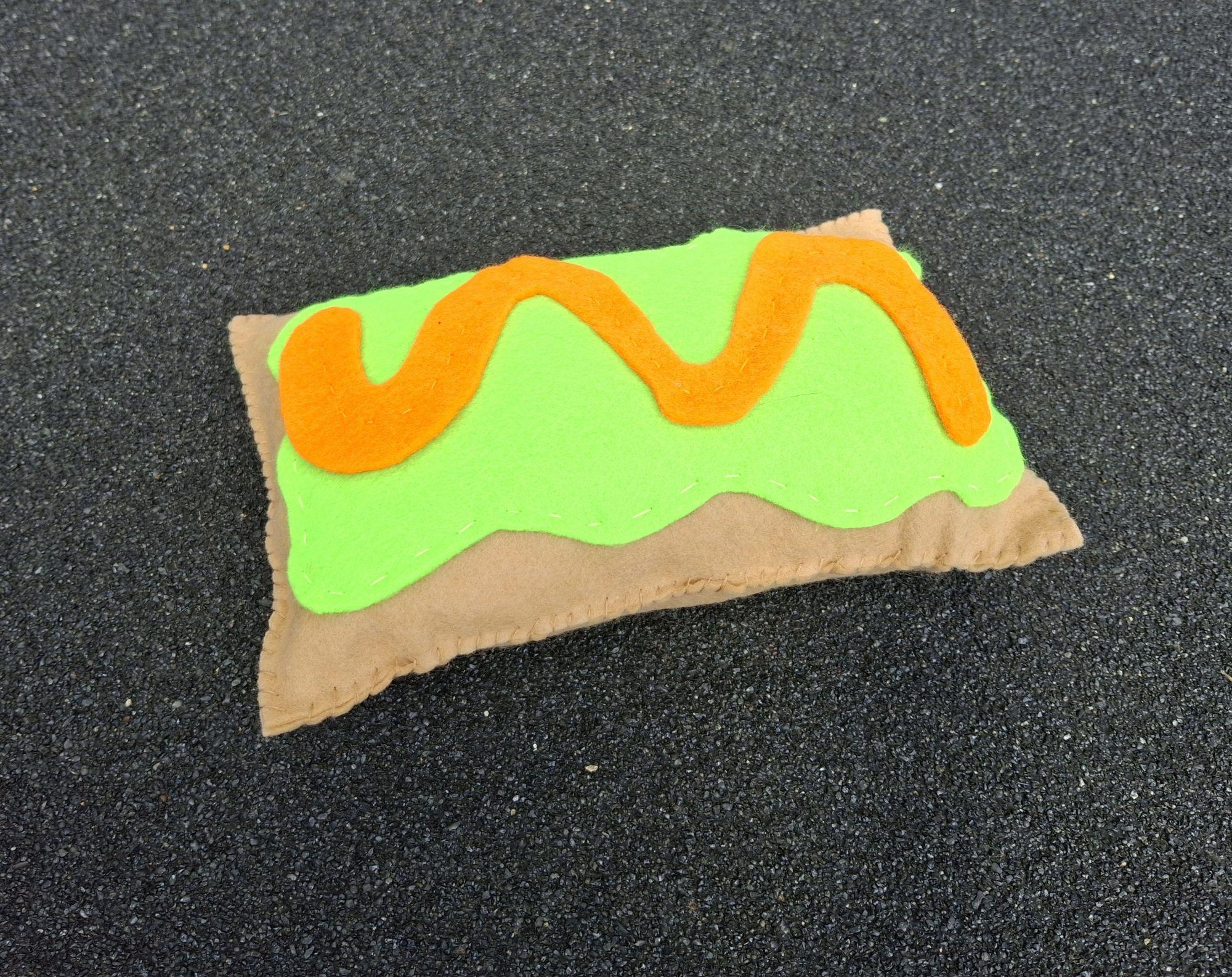 Hand sewn felt pop tart pillow with brown base, green top, and orange wavy line. / Hand sewn felt pop tart for 7th grade art class. 