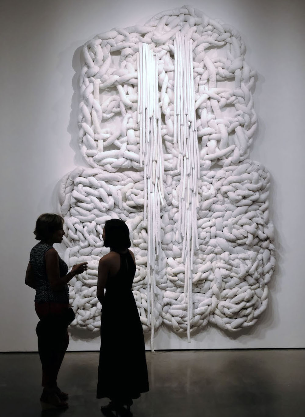 image of large textile piece with two people speaking in front of it