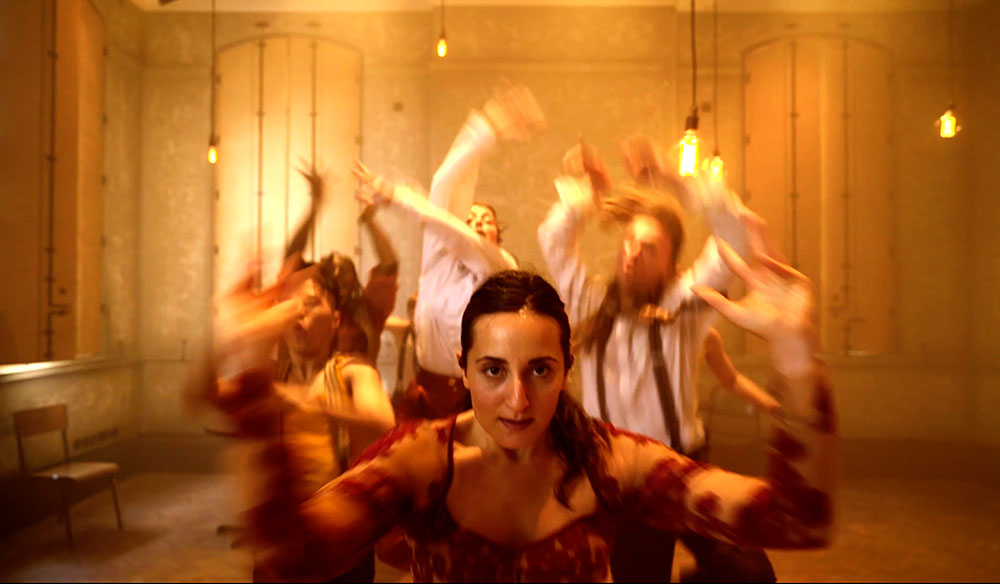 image of woman staring at the camera with dancers blurred in the background