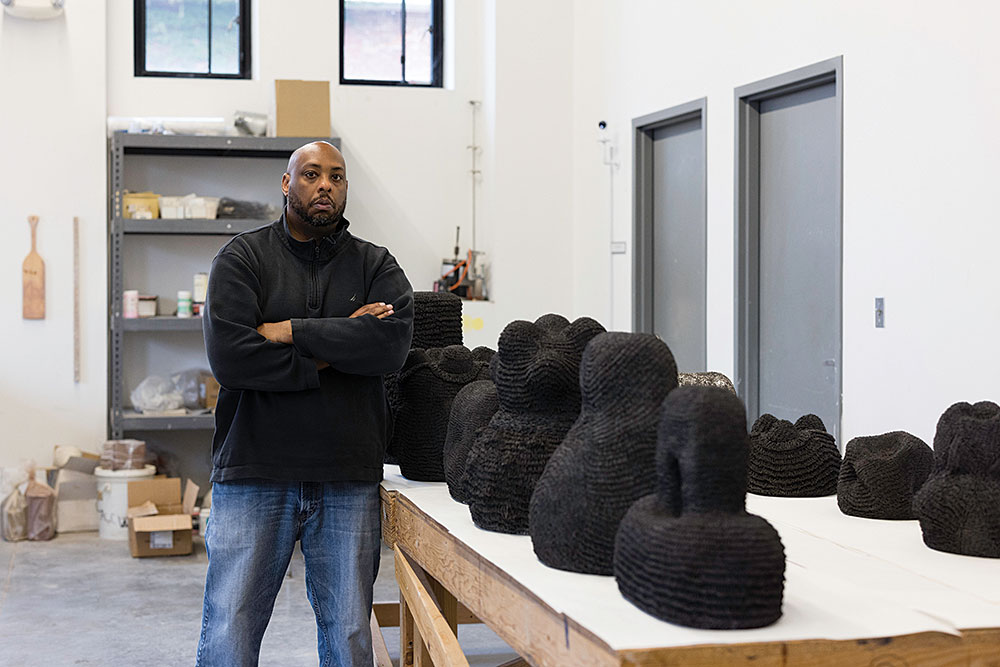 image of Donté K. Hayes next to his fired pieces of art. 