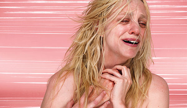 blonde woman crying holding a hand on pink background