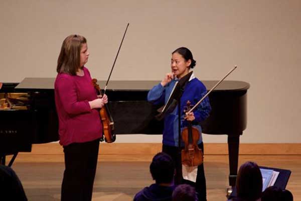 Midori on stage speaking with student vionlist