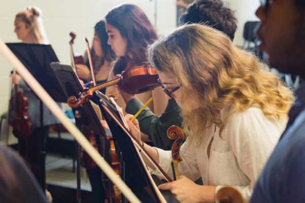 violin students writing notes on sheet music