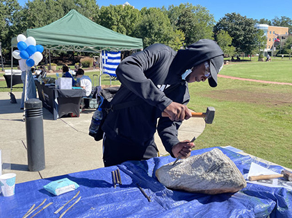 student hitting a stone with a chisel and hammer