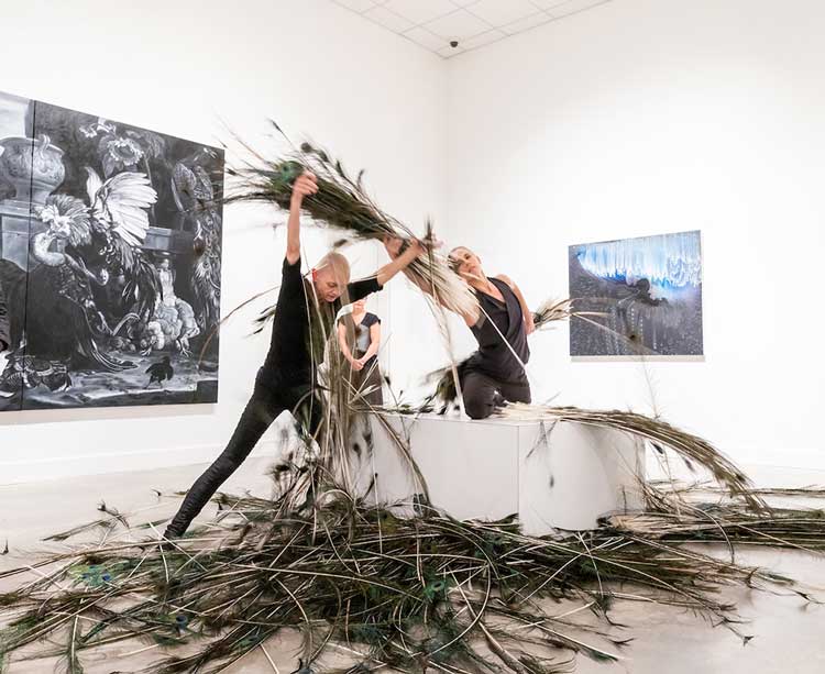 Photo of dancers Lisa Lock and Autumn Eckman performing in the Zuckerman Museum of Art Galleries with peacock feathers