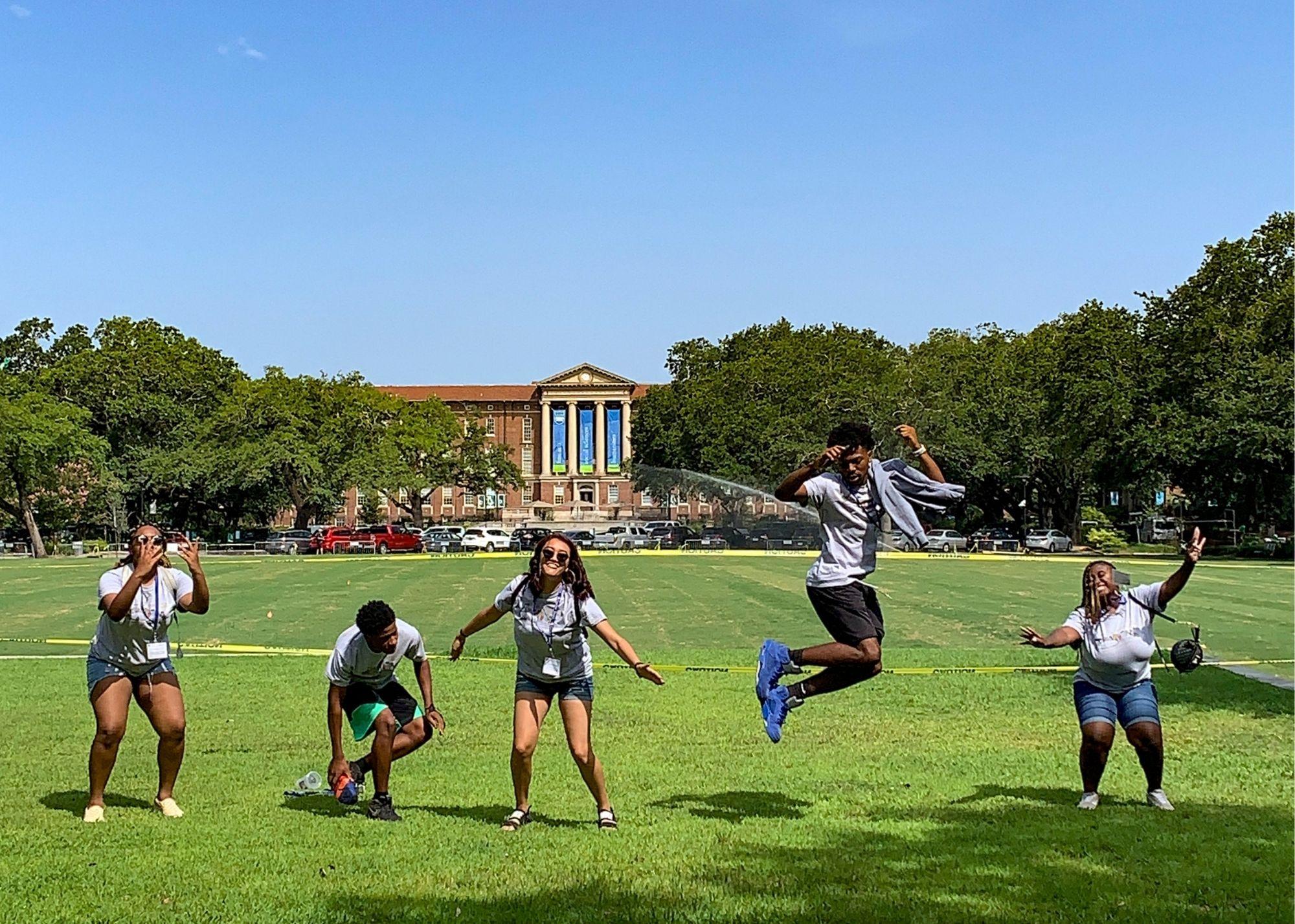 Students on a field smiling and jumping in the air. / KSU TRIO Students have the opportunity to go on an out of state, educational field trip after full participation in the KSU TRiO Summer Academy. The trip is provided at no cost to students.