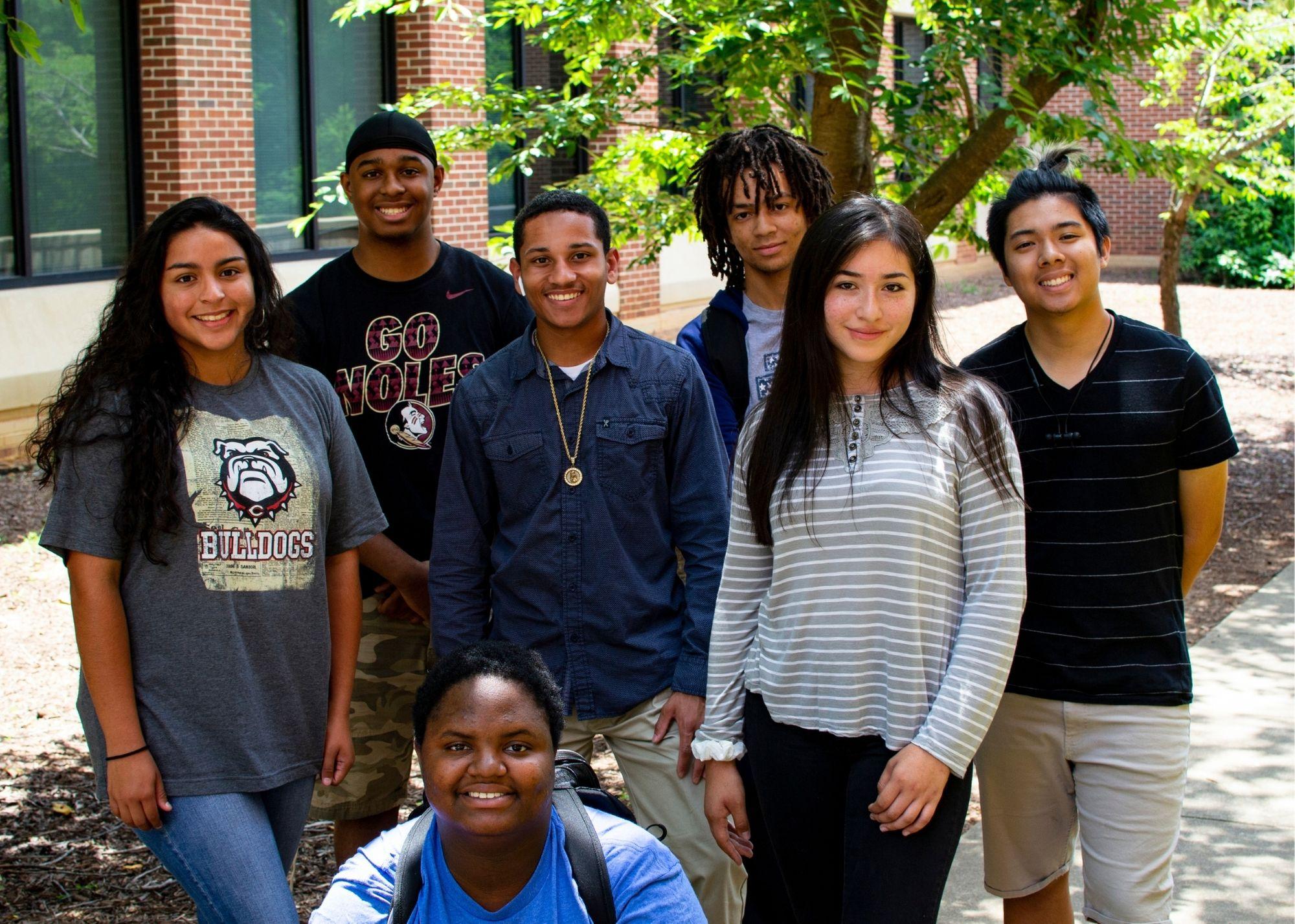 Students smiling and standing outside underneath a tree / KSU TRiO works with Georgia Highlands College to provide scholarships for KSU TRiO Seniors to receive two free college courses upon graduation