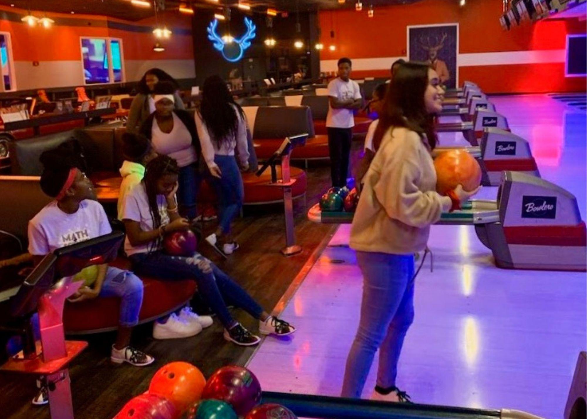 Students at a bowling alley, bowling. / KSU TRIO students learn the physics behind everyday activities like bowling.
