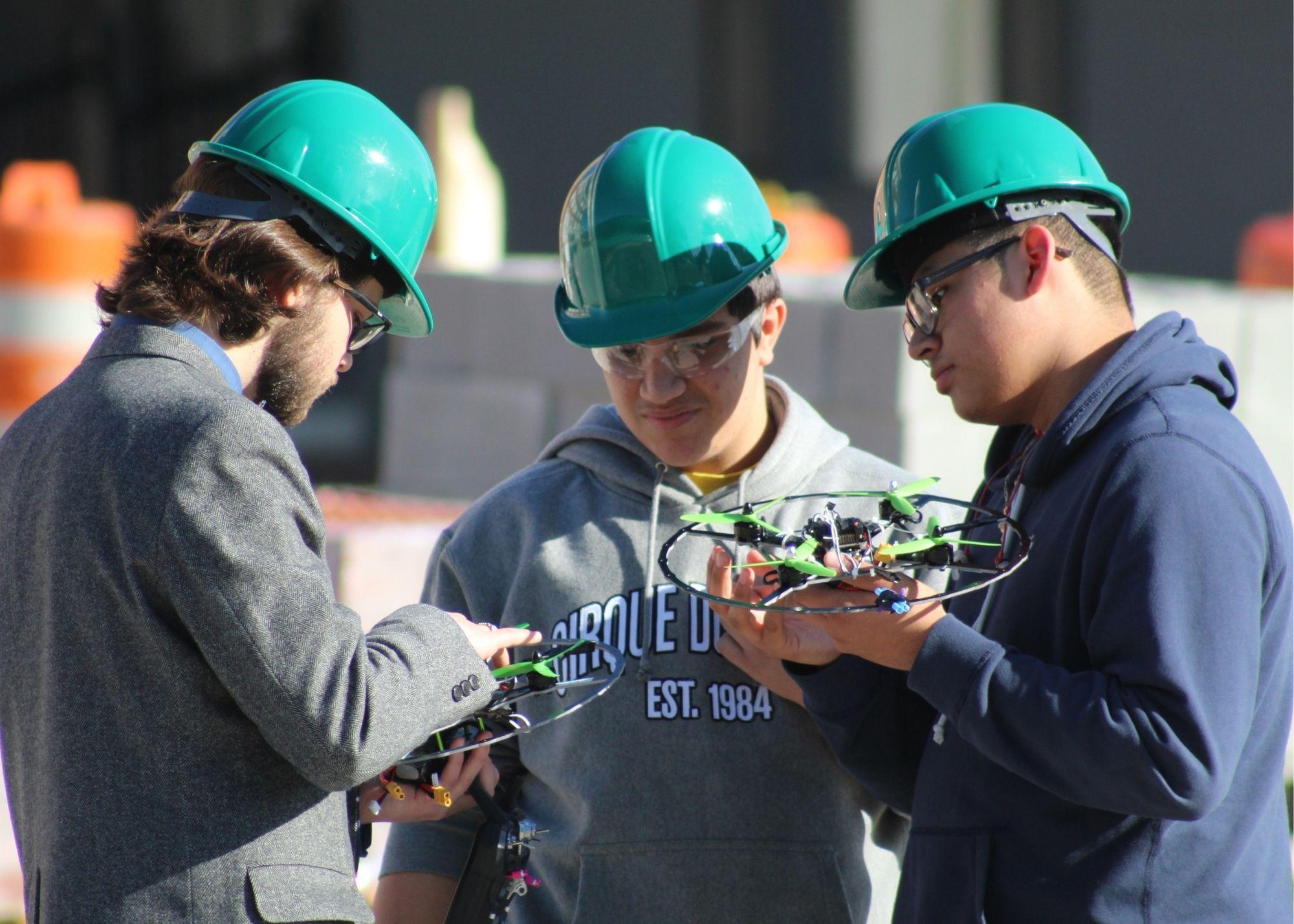 Three students wearing hardhats and holding drones / KSU TRIO's groundbreaking Drone Program introduces students to the basics of drone flying, ethics, and mechanics, and the program gives students the opportunity to test for their FAA Pilot's License