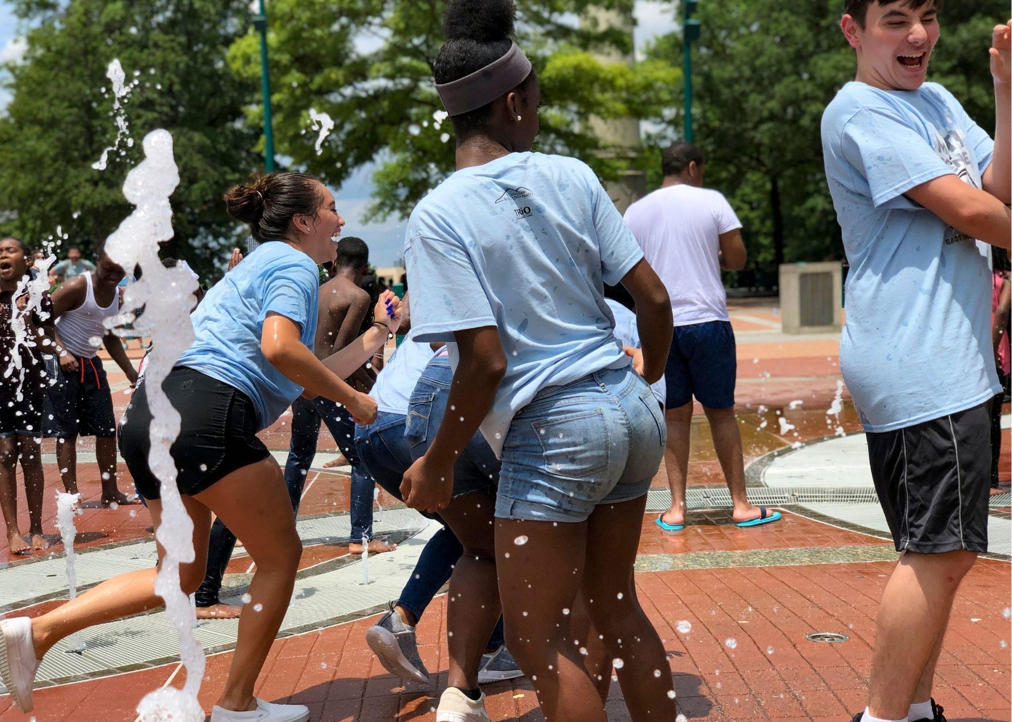 Students laughing and playing in a water fountain. / KSU TRiO visits Georgia State University, the Civil Rights Museum, and Centennial Park.