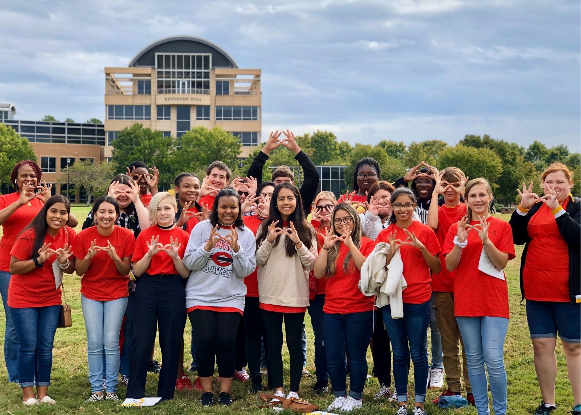 Students in red shirts pose outside in front of the Kennesaw Hall building at KSU / KSU TRiO Upward Bound at Rockmart and Cedartown High Schools visit Kennesaw State University.
