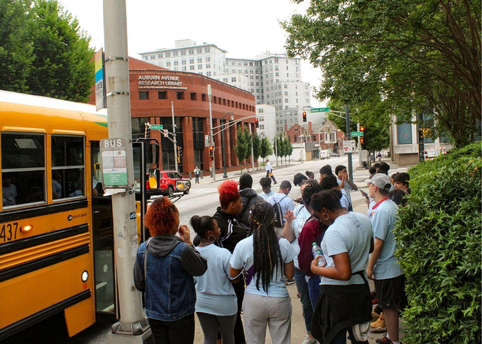 Students standing outside near a school bus. / KSU TRiO visits Georgia State University, the Civil Rights Museum, and Centennial Park.