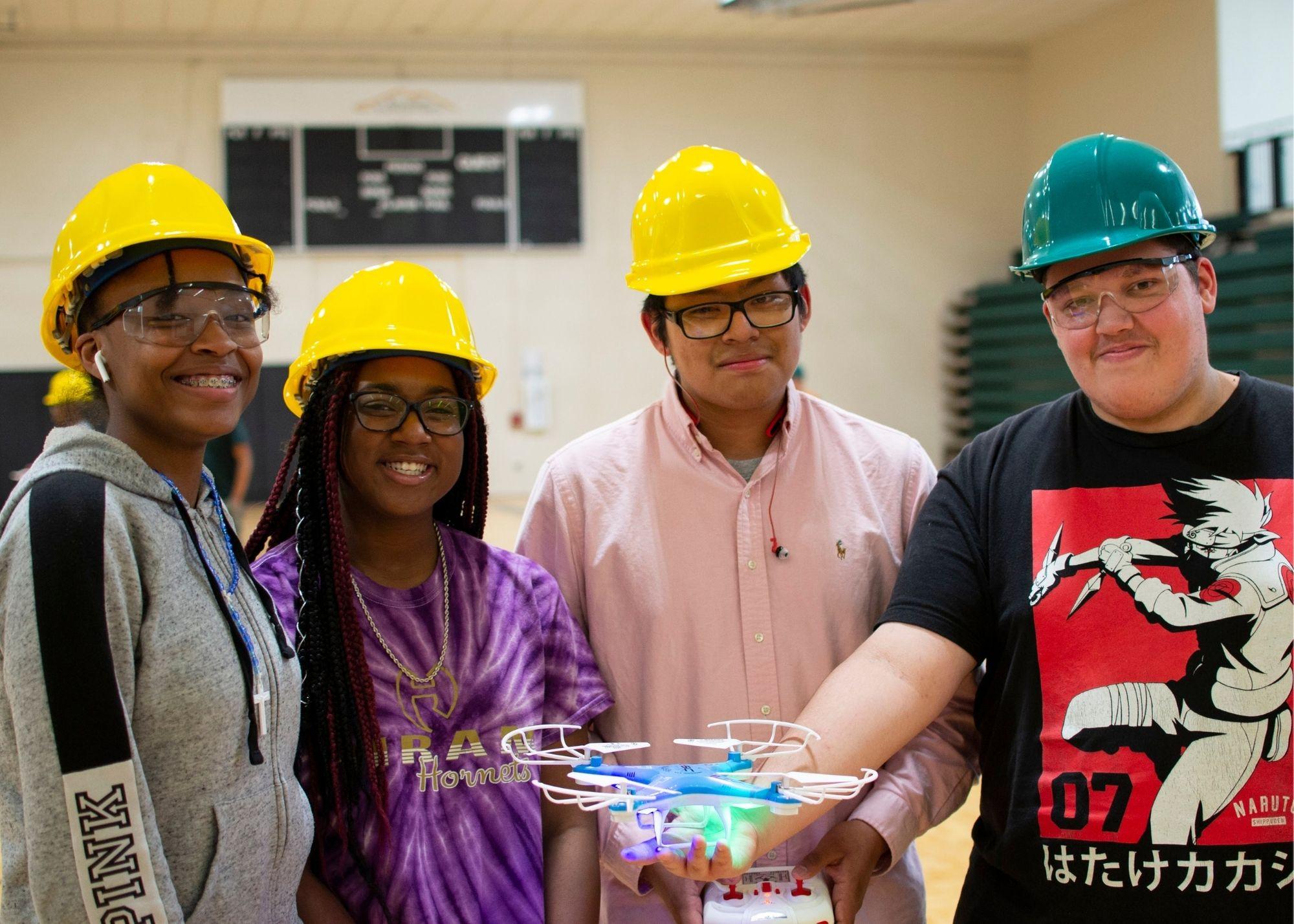 Students wearing hardhats, with one student holding a remote and the other holding a drone / KSU TRIO's groundbreaking Drone Program introduces students to the basics of drone flying, ethics, and mechanics, and the program gives students the opportunity to test for their FAA Pilot's License