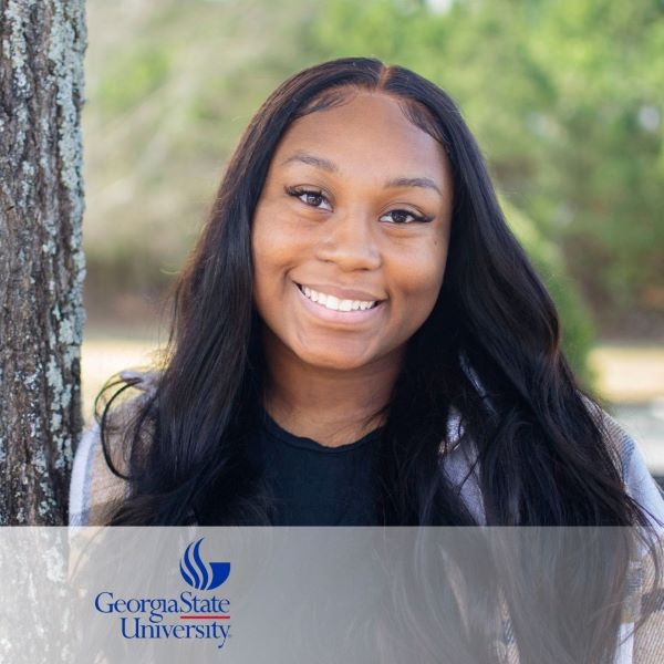 Ashley Hoillett, a smiling student standing next to a tree, with the Georgia State University logo in the bottom left corner.