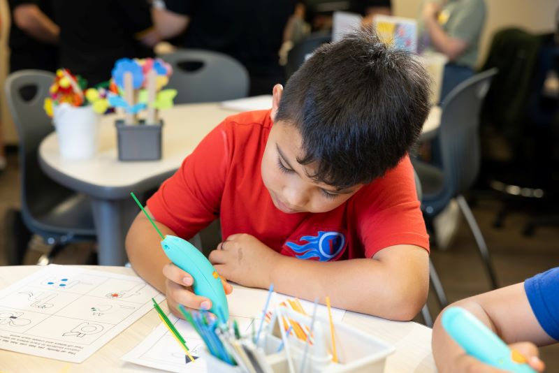 Young student sitting at a desk doing a painting exercise.