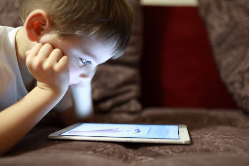 Young boy staring at a tablet