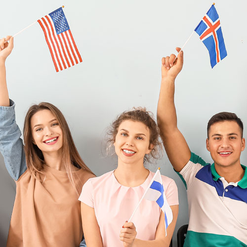 Four enthusiastic participants holding flags and smiling, showcasing the spirit of International Field Experiences.