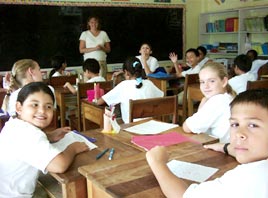 A teacher instructs students at desks in a classroom during an international teaching exchange program in Belize.