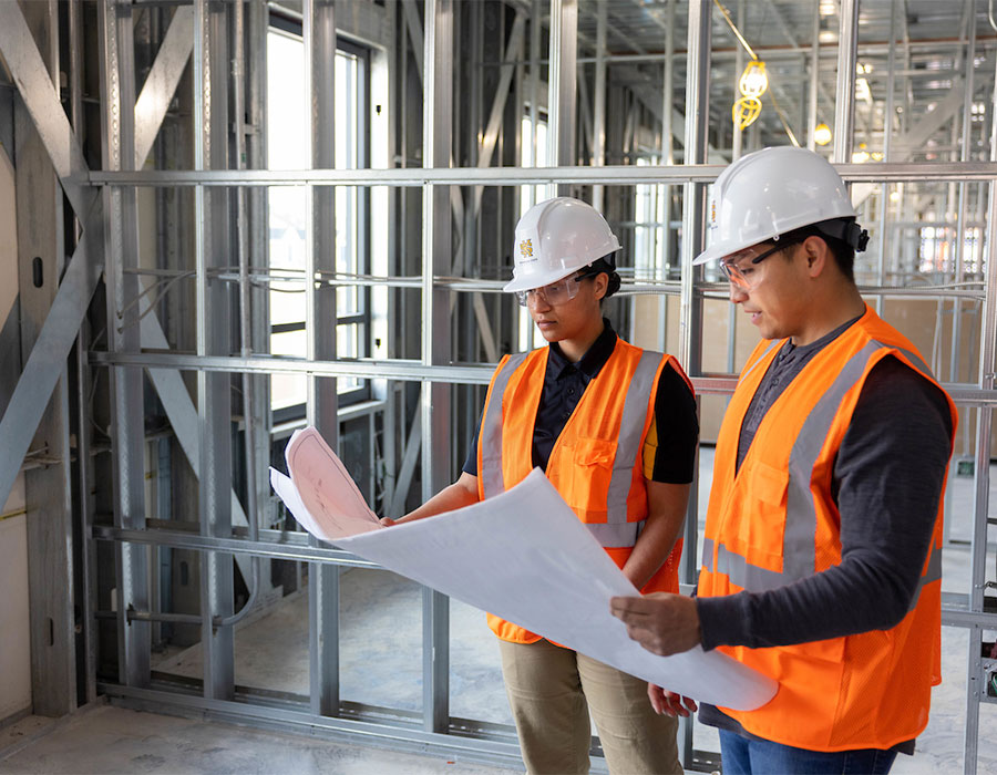 ksu construction management students on a construction site with safety gear on looking at blue prints