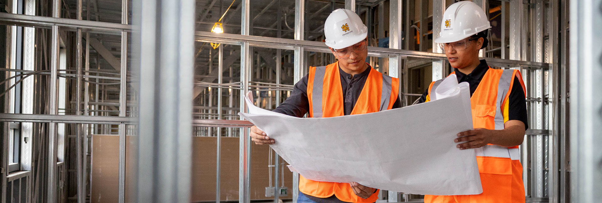 construction management students on job site reading blueprint 